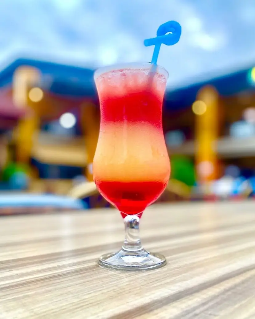 Un cocktail rouge et orangé dans un verre tulipe.