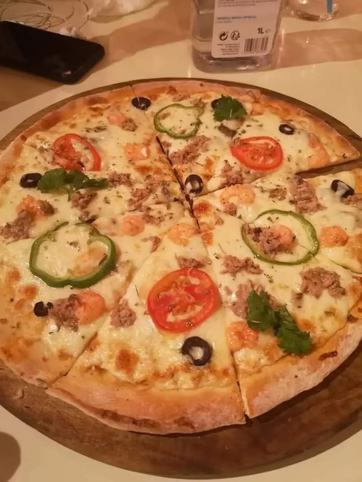 Une pizza aux tomates et poivrons sur une planche en bois.